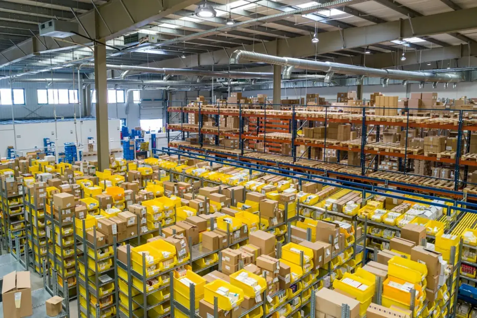 Raflar arasında koli ve paletlerin düzenlendiği büyük depo
